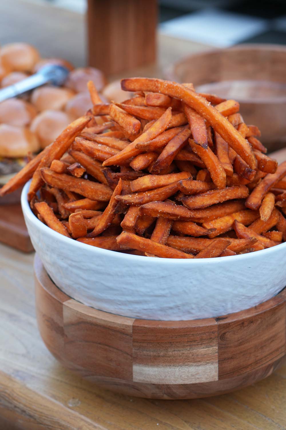 A bowl of sweet potato fries on a wooden table