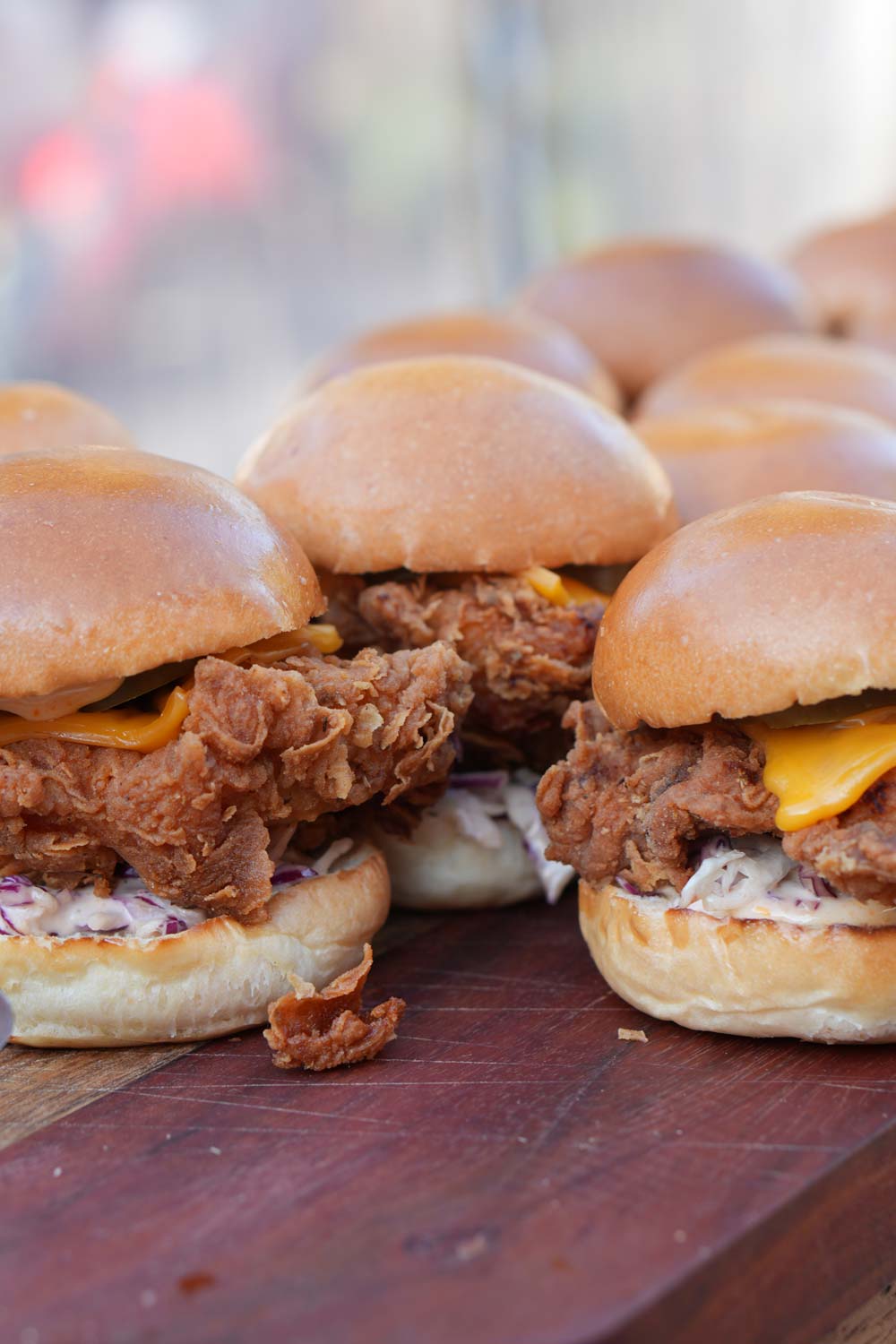 A photo of a bunch of crispy chicken sliders sitting on a wooden board