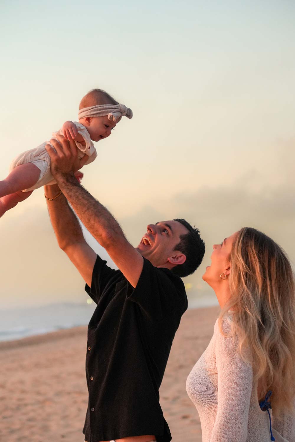 A joyous mother and father lifting their newborn into the air